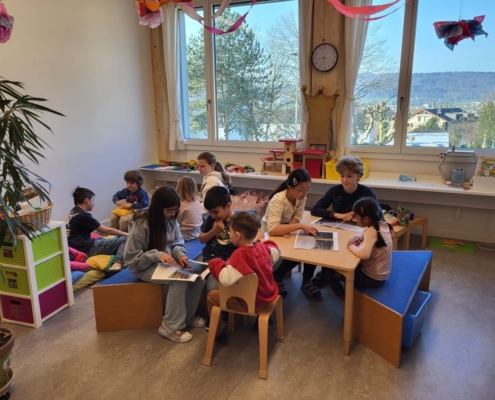 viele Kinder hören zu im Gruppenraum