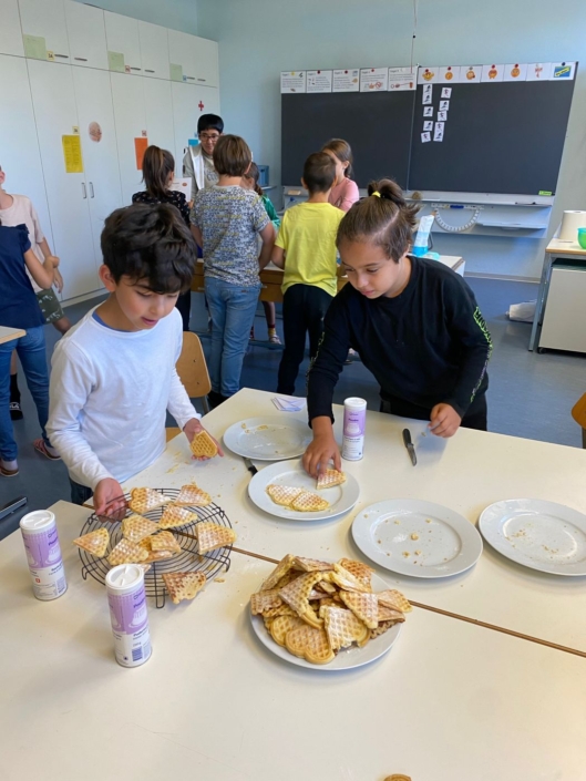 Zwei Jungen bestreuen Waffeln mit Zucker