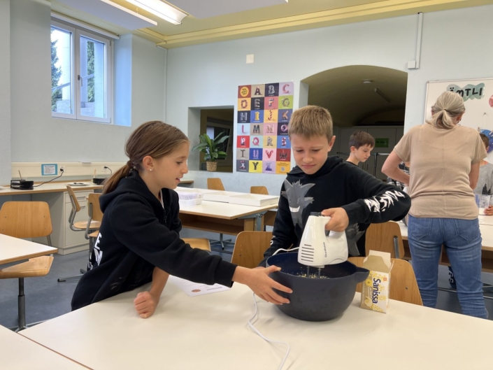 Zwei Kinder mixen den Teig