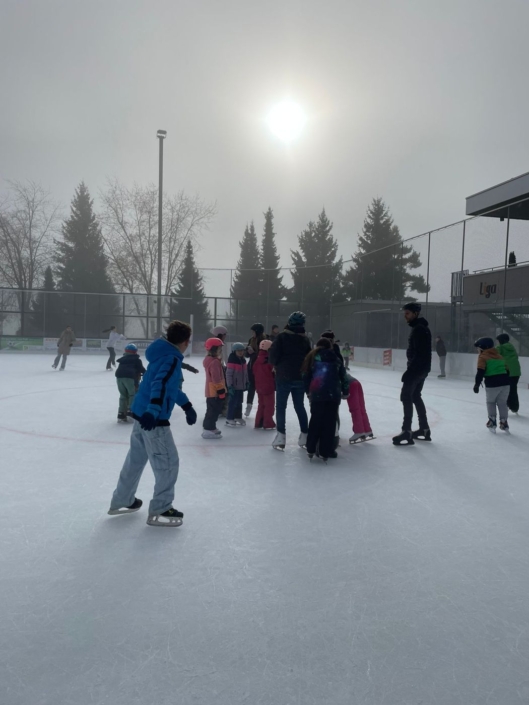 Eine Gruppe Kinder steht zusammen auf dem Eisfeld.