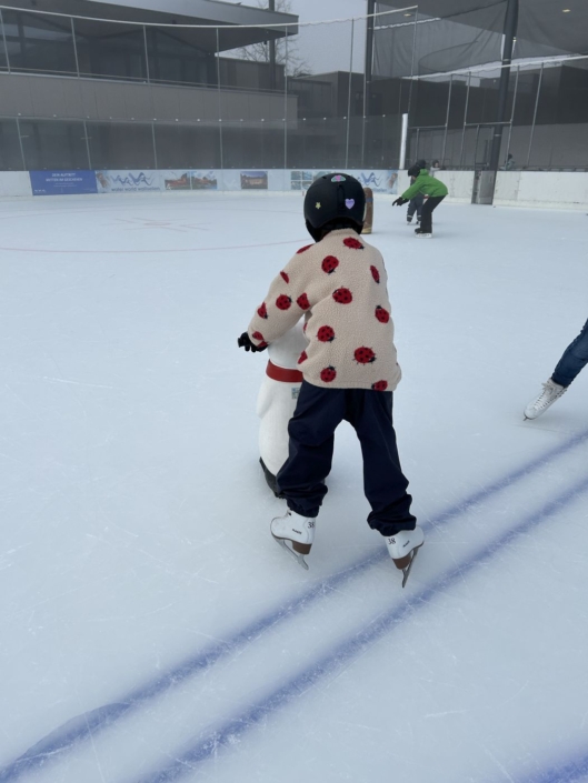 Man sieht ein Kind von hinten, wei es einen Pinguin als Hilfe benutzt.