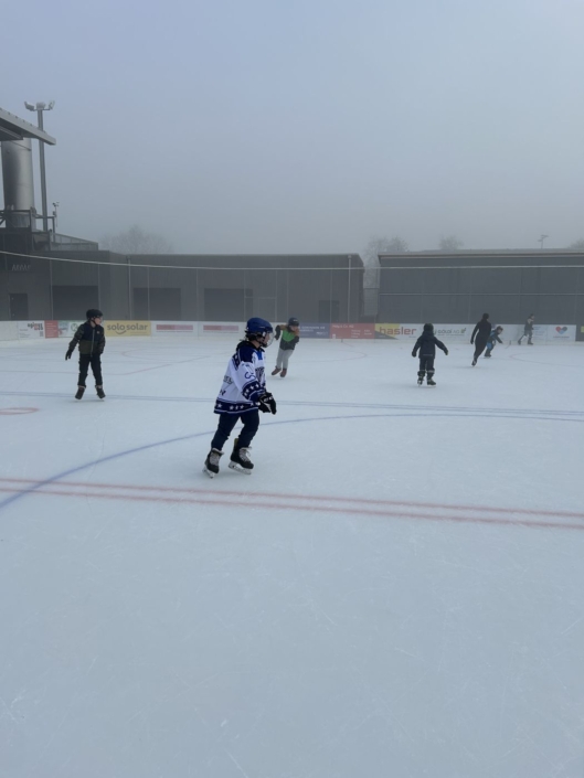Mehrere Kinder sind auf dem Eisfeld.