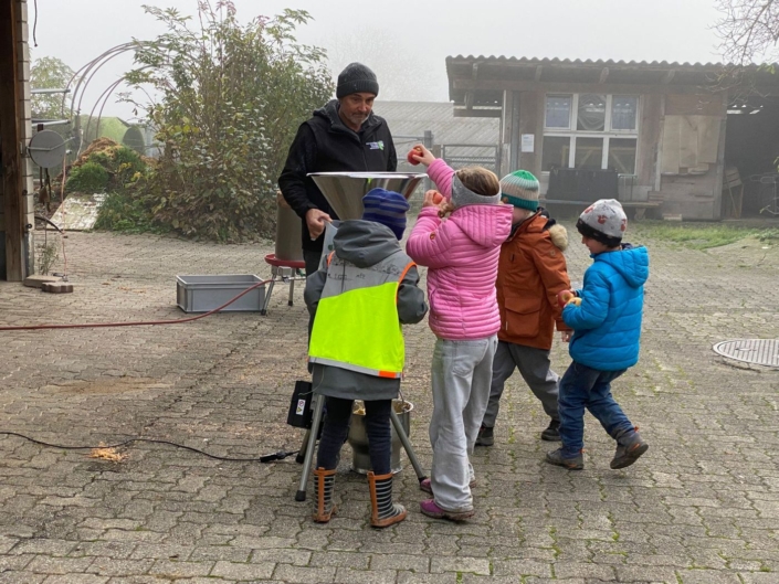 Die Kinder werfen Äpfel in eine Maschine
