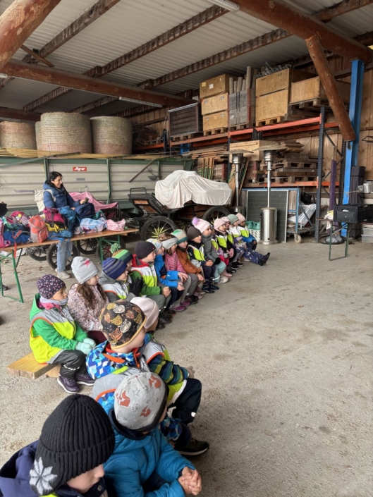 Die Kinder sitzen in der Scheune und hören gespannt zu