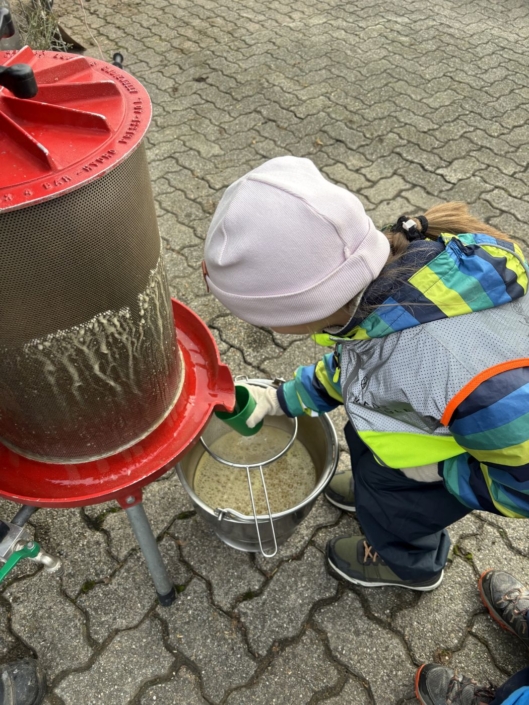 Ein Kind fängt eine Flüssigkeit aus einer Maschine mit ihrem Becher auf.