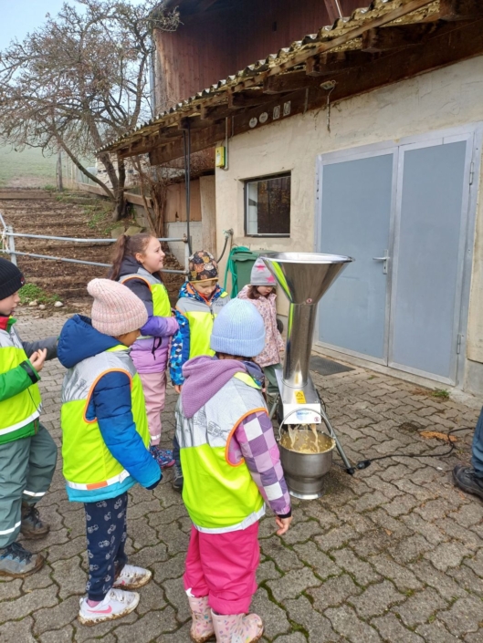 Die Kinder schauen zu, wie aus einer Maschine eine hellgelbe Flüssigkeit rauskommt.