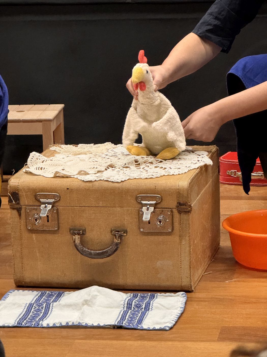 20260324_Werkgeschichte_UST_10 Huhn Gackita sitzt auf dem Koffer